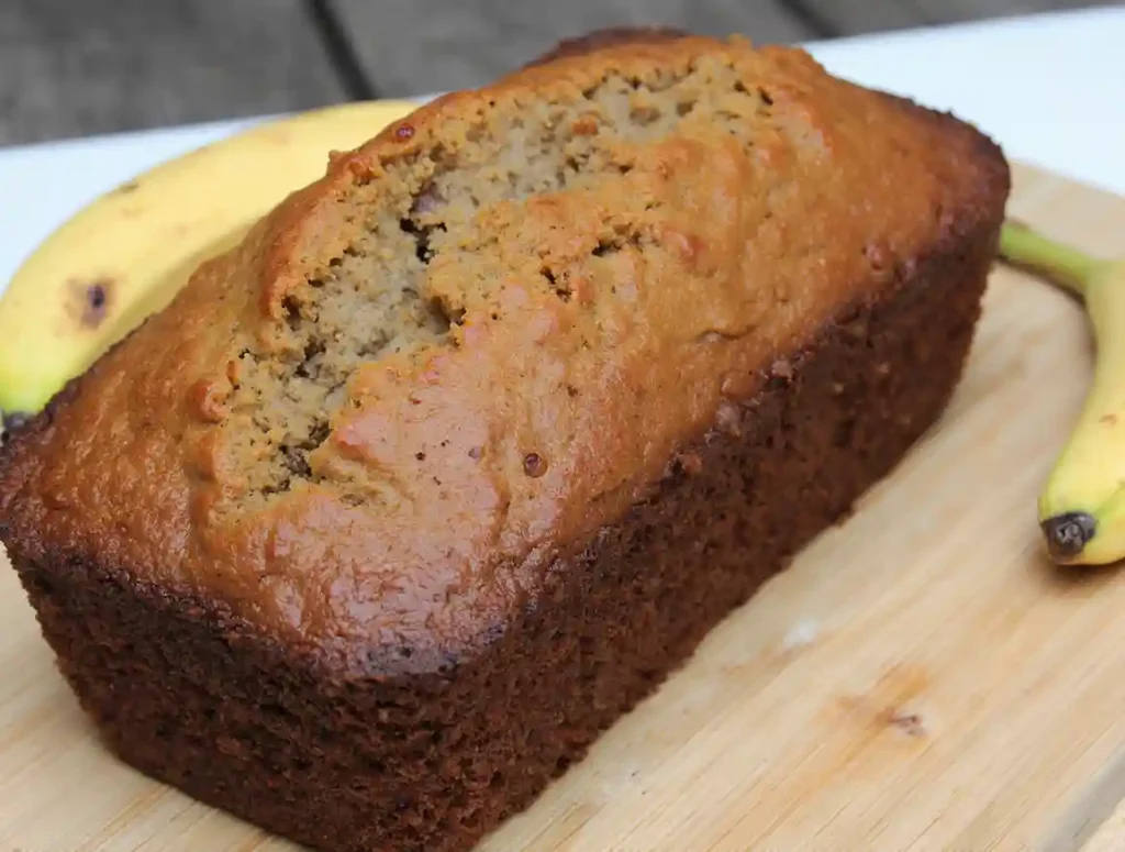 A freshly baked loaf of banana bread lout from the oven .