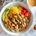 Burger bowl with rice topped with beef, cheese, and veggies