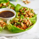 Warm chicken filling spooned into crisp lettuce leaves for a fresh and light lunch.