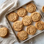 almond flour peanut butter cookies fresh from the oven, showing that classic fork-press crosshatch and a scatter of flaky salt