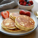 A golden stack of cottage cheese pancakes topped with fresh strawberries